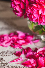 red peonies in glass vase stand on table