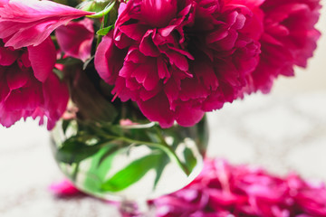 red peonies in glass vase stand on table