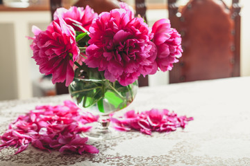red peonies in glass vase stand on table