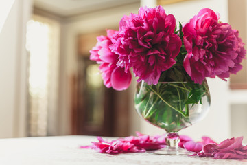 red peonies in glass vase stand on table