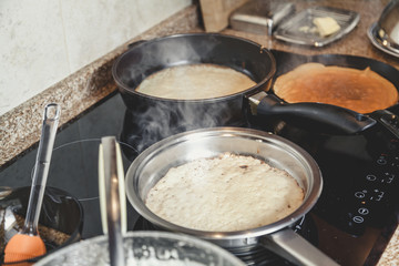 cooking pancakes in several pans