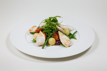 Seafood Salad with tomato and calamari on a white plate on a white background isolated