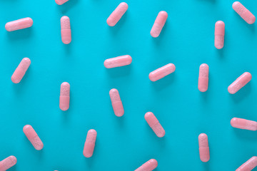 pink pills on blue background top view