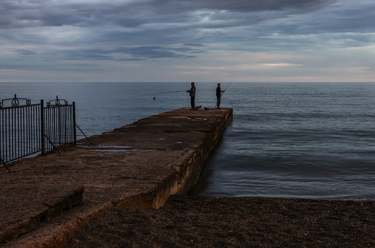Group of fishermen on a pier at sunset. Crimea peninsula