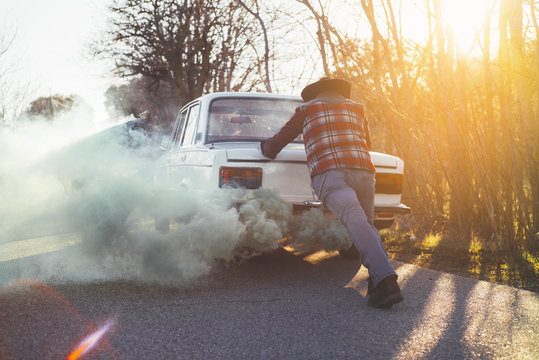 Man pushing broken vintage car