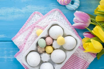 Fototapeten Pasen gekleurde eieren. Een boeket van verse lente tulpen. Blauwe achtergrond Sweets. Briefkaart, vrije ruimte voor tekst. © Marina