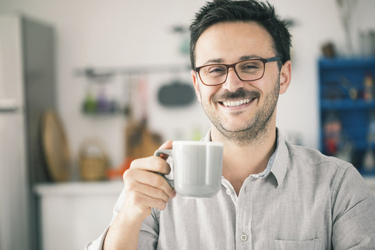 Happy smiling man looking camera and having cup of coffee