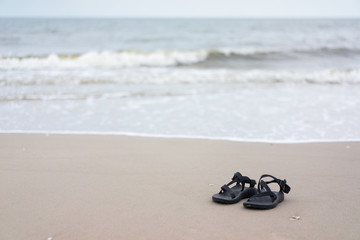 Fototapeta na wymiar selective focus of black sandal on the beach