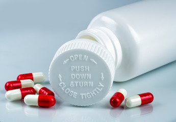 Capsules pills on white background and plastic bottle with blank label and copy space. Childproof...