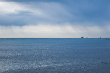 a cloudy day at sea. birds flying low in the distance the ship