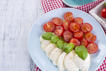 Traditional Italian salad with fresh cherry tomatoes and soft mazarella cheese, with basil and olive oil. Ingredients for salad.