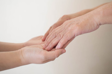 National Family Caregiver Month. Close up of young female caregiver hand holding senior hand....