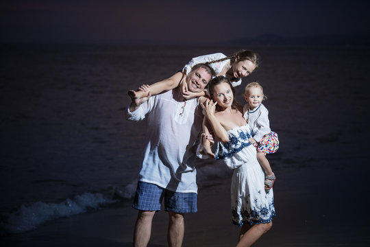 Family father, mother, child girl and baby on the beach against the sea and the sunset beautiful and happy