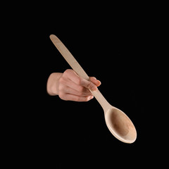 cropped image of woman holding wooden spatula in hand isolated on black