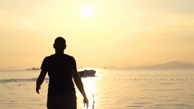 Silhouette of man walking on beach during sunset, super slow motion 240fps
