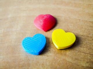 Three hearts on wooden background. Photo of 3d-printed objects.