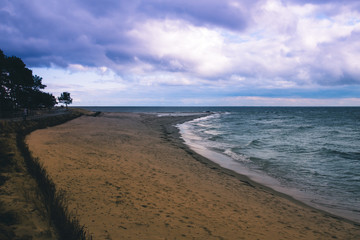 Empty sandy sea beach at dusk at sunset, before the storm