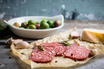 Delicious salami with olives, spices and rosemary. Selective focus.