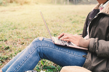 Enjoying moment woman backpacker using laptop in beautiful forest background, Relax time and work anywhere concept  ,color of vintage tone and soft focus