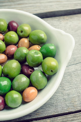 Fresh olives in white plate on the rustic background. Selective focus.