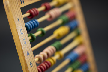 Wooden abacus / educational counting toy with 100 beads; on black background, closeup.