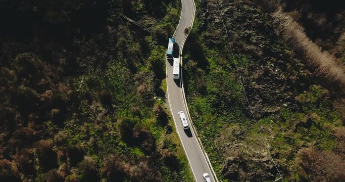 Aerial view of vehicles on a narrow mountain road. Tour bus stops at roadside to let oncoming cars pass. Safety. 4K.