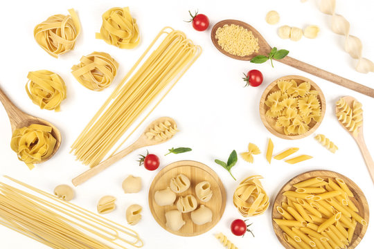 Overhead photo of different types of pasta with tomatoes and basil on white with copy space