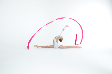 Rhythmic gymnastics caucasian blonde girl in dress for show performing athlete exercises with pink...