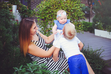 woman mother with two young children lie on a green lawn, entertain the girl, the concept of motherhood and the upbringing of children