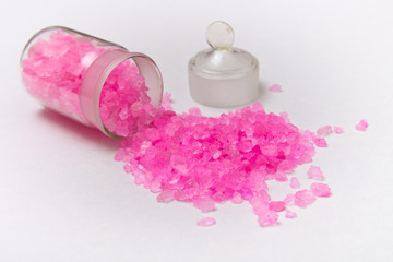 Bath salt. Pink crystals of salt crumbled from a jar on a light background