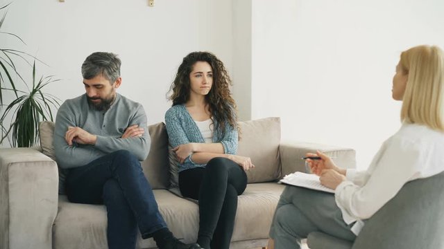 Married couple listening professional psychologist and trying to solve relationship porblems during visit psychotherapist office