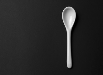 A clean white ceramic spoon isolated on a black background.