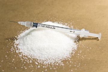 Insulin syringe and lots of sugar on gold background. The concept of diabetes
