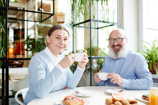 Happy senior man and woman enjoying aromatic tea and yummy dessert in cafe - Powered by Adobe