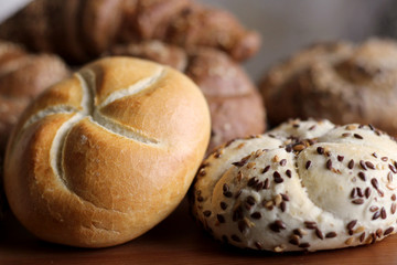 Tasty freshly baked butter kaiser roll with linseed and sunflower seeds. Top view, copy space, selective focus. Pastries on a wooden table. Blurred background. Concept of fresh pastry.