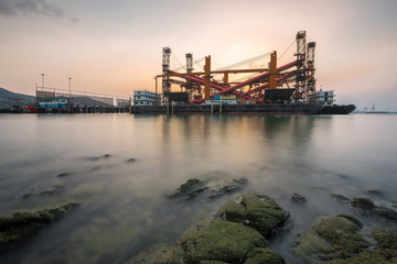 Obraz premium Crane barges or crane pontoons docked at the pier near the coast in the evening.
