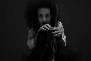 black and white portrait of young musician with acoustic guitar looking at camera