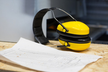 industrial earmuffs and bill on table at workshop
