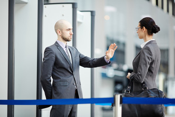 Young airport security staff stopping young traveler with hangbag on entrance