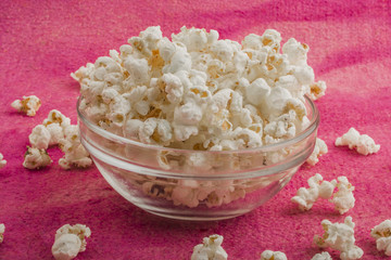 popcorn in a glass plate, on a pink background