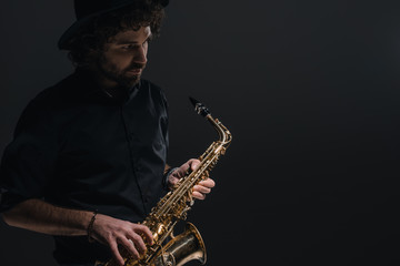 Naklejka premium young musician playing saxophone on black