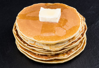 Stack of pancakes in syrup on dark background