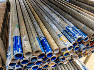 Mental scaffold pipe stack together on scaffold plank wood shelve with blue, green and yellow mark at the tip for build the temporary structure.
