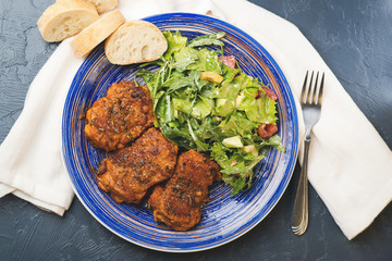 Platter of chicken thighs piri piri coated in hot sauce with salad.