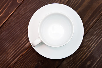 Empty white Cup with saucer on a wooden background, top view . Crockery for coffee and tea