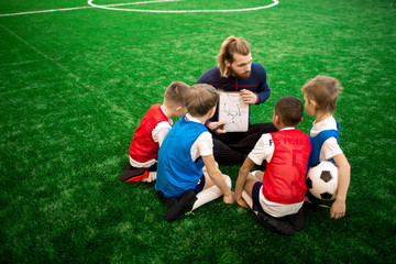 Young trainer showing his football team sketch of moving scheme while preparing for competition