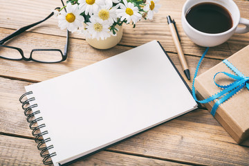 Gift box and a blank empty notebook, office desk background, view from above, copy space