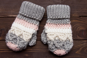 Fototapeta na wymiar Warm knitted gloves on wooden background. Clothes for winter.