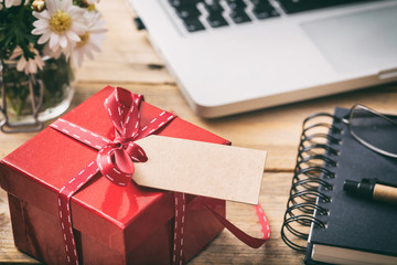 Red gift box with empty blank tag, blur office desk background