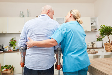 Physiotherapeutin hilft Senior an Krücken